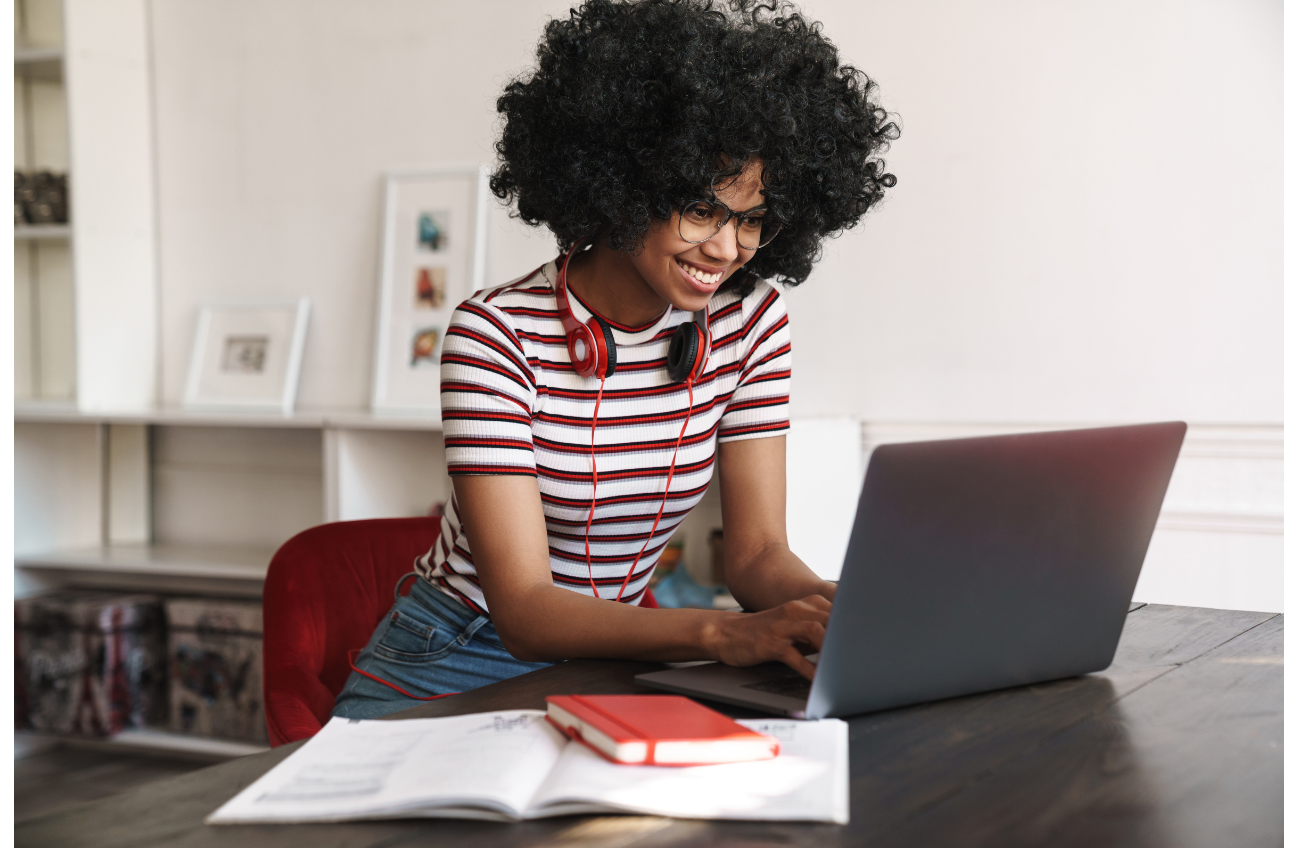 A dedicated researcher immersed in their research journey, working on a laptop with open books and notes at hand. The study space is filled with framed pictures and shelves, creating an atmosphere of focus and exploration.